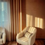 Fotoliu confortabil scăldat în lumina soarelui, capturând atmosfera hygge specifică unui design interior scandinav.